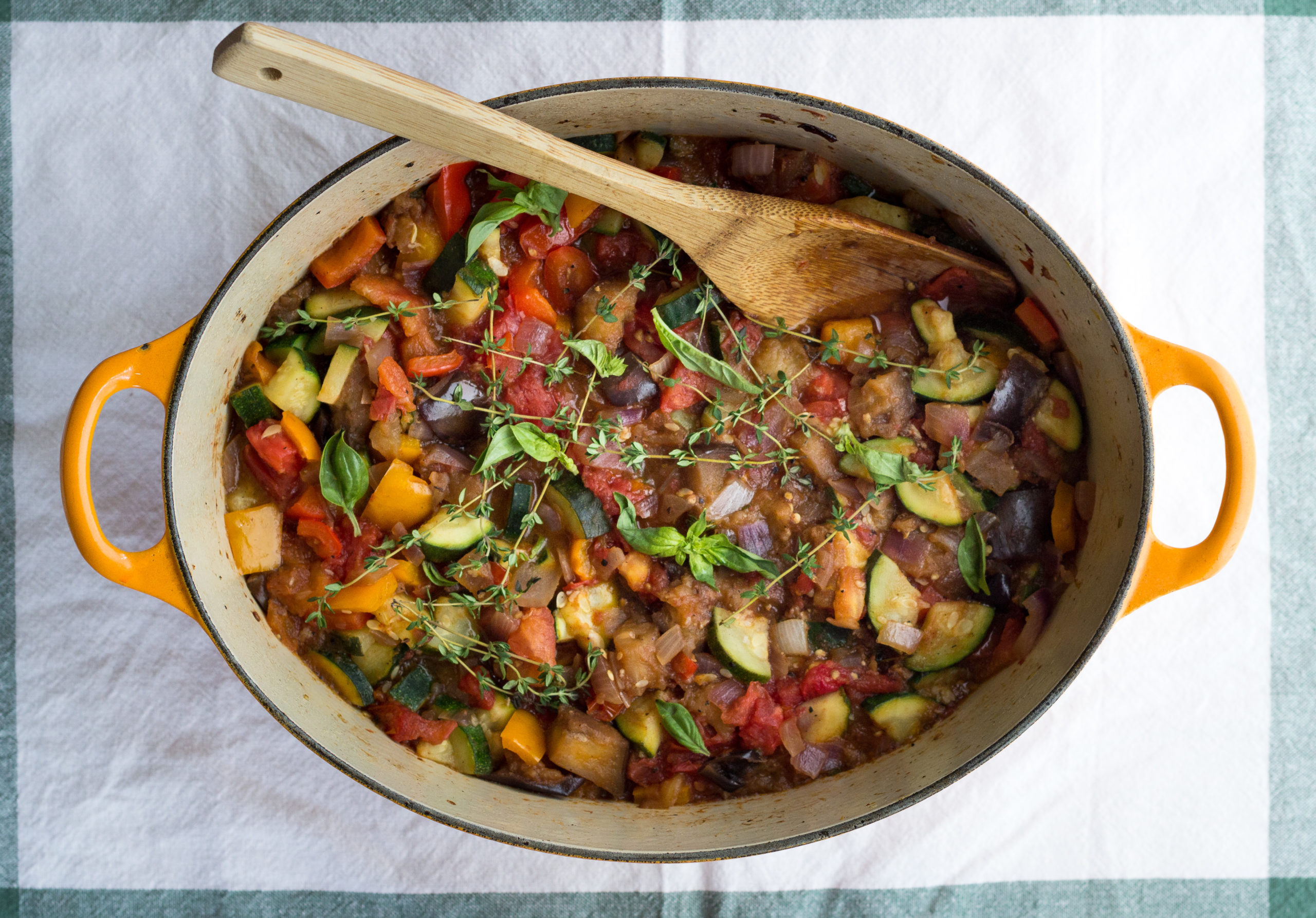 Overhead view of rustic stew in large dutch oven pan with a wooden spatula