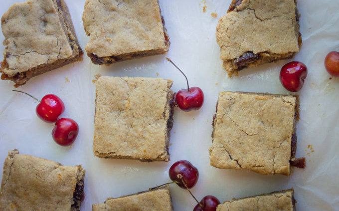 Birds eye view of a group of cut up Cherry Jubilee Blondies with fresh cherries around them