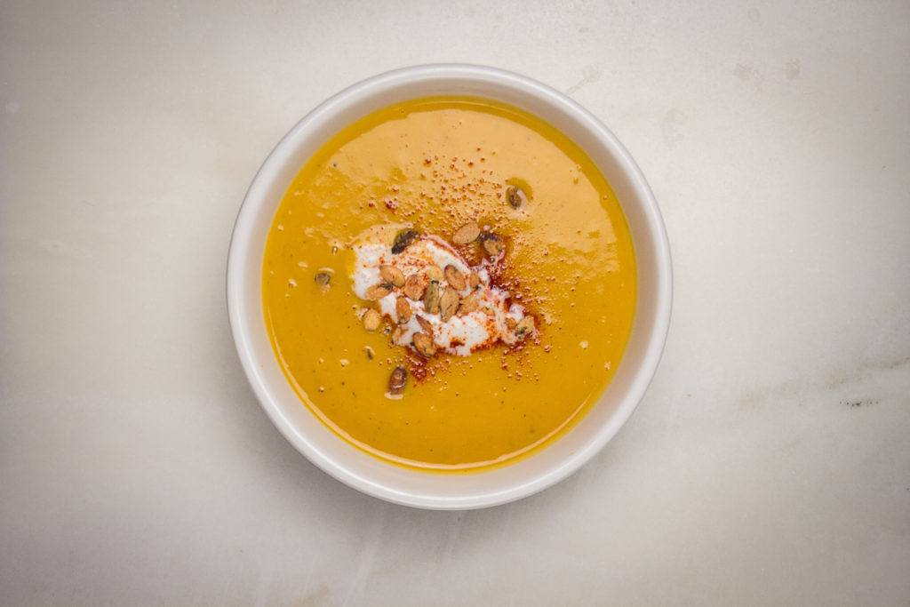 Overhead view of a bowl of creamy butternut squash soup top with roasted pumpkin seed
